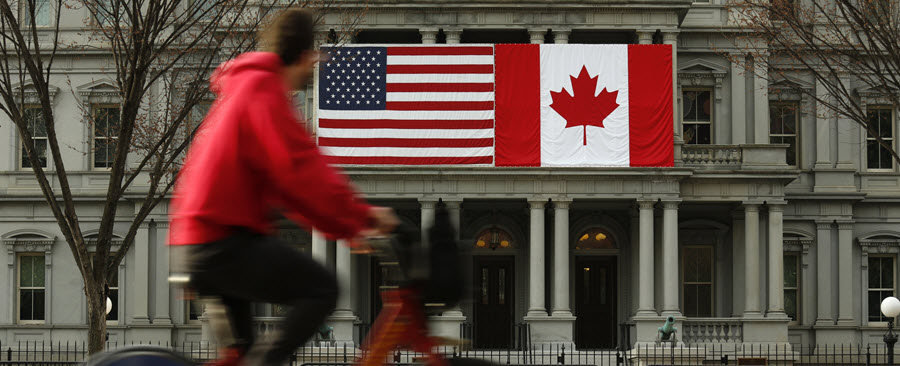 Person riding a bike with the Canada and U.S. flags in the background.