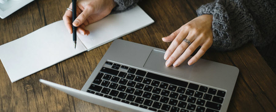 Woman working at her desk with a laptop and notebook.