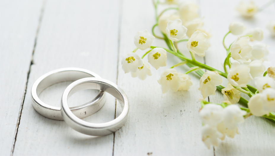 A photo of weddings rings and white flowers.