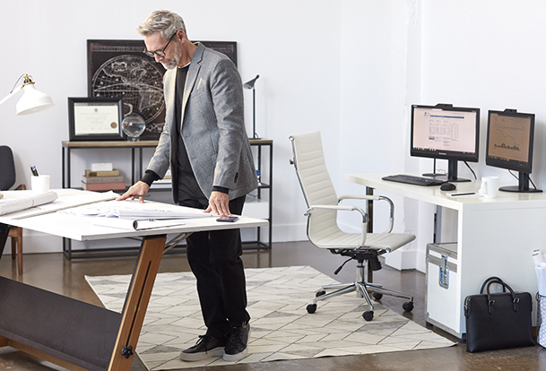 Un homme travaille debout à son bureau.