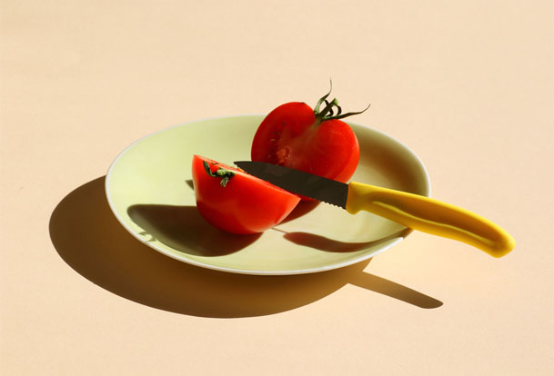 Deux moitiés de tomate dans une assiette et un couteau