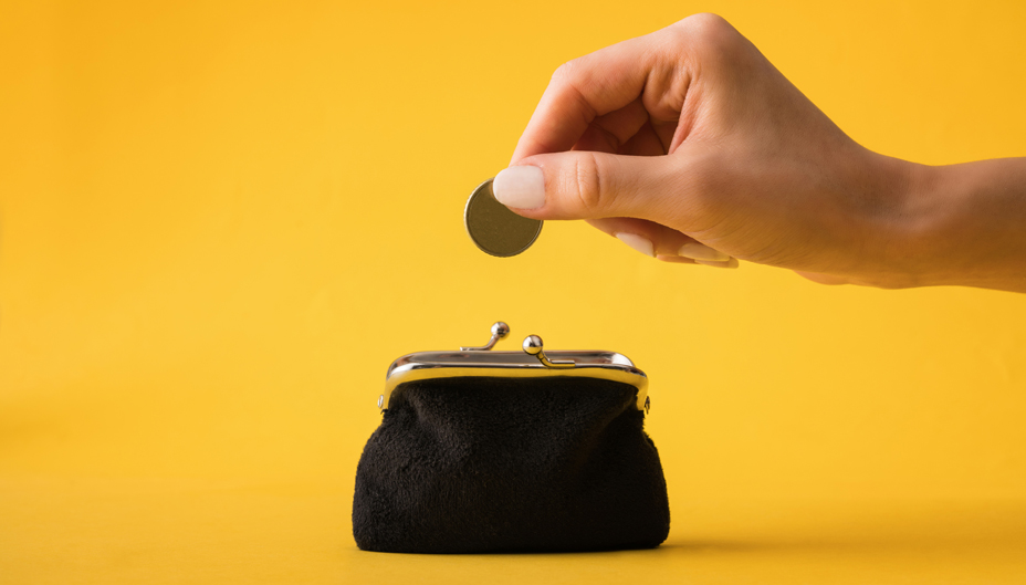 A hand dropping a coin into a purse.
