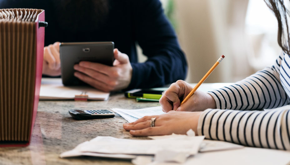 A couple at a cluttered table, working on their taxes.
