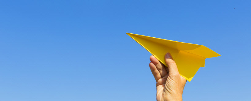 Person holding a paper airplane to the sky. 